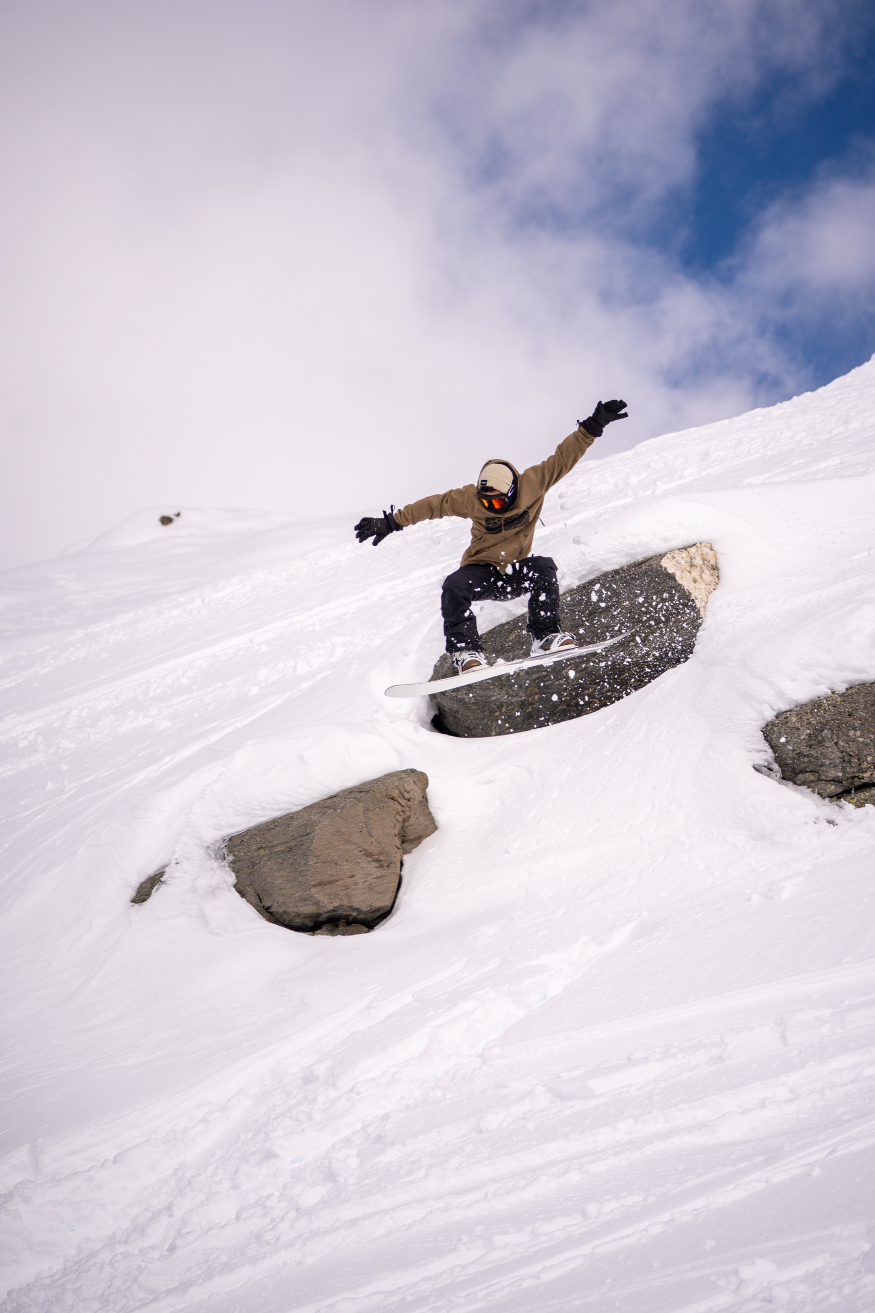 Snowboarder grabbing the board over an exposed rock face