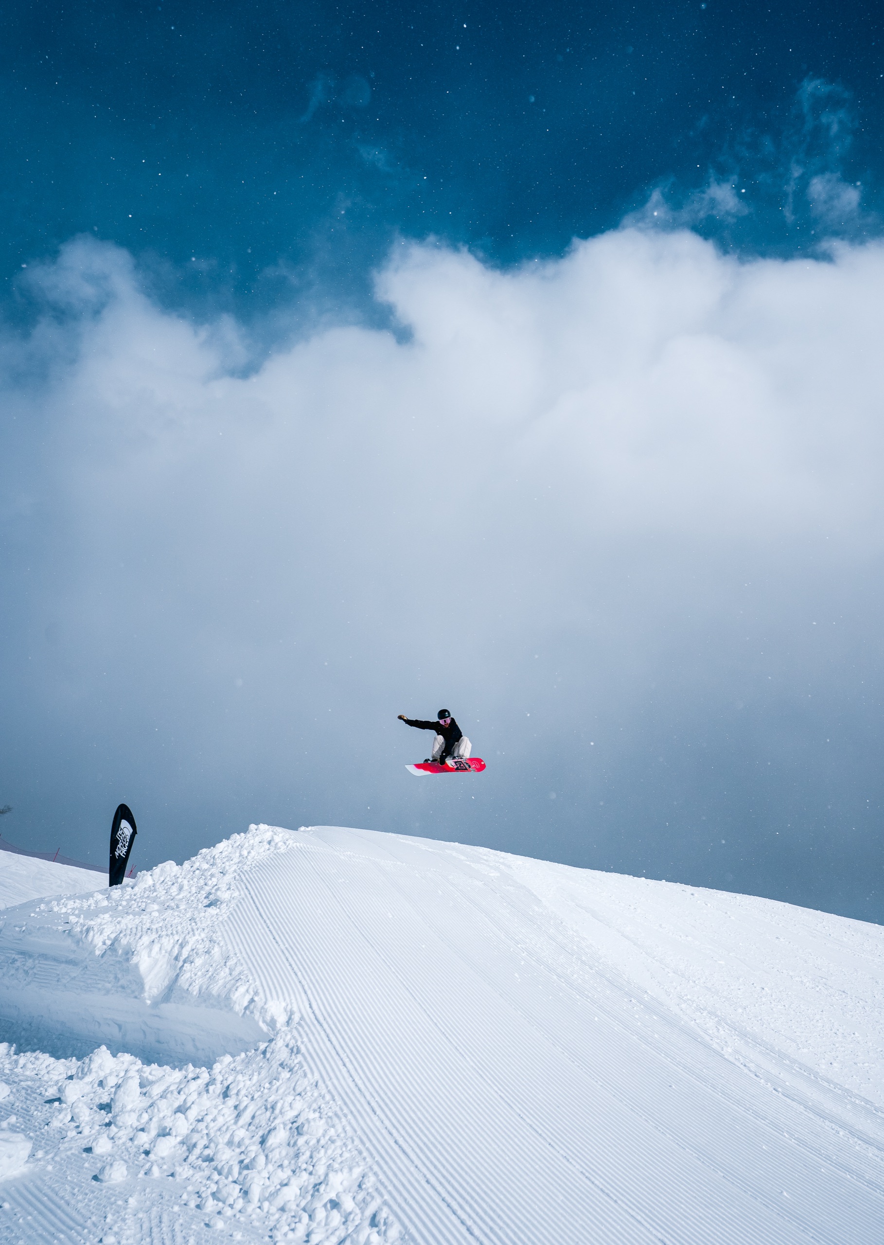 Snowboarder launching off a lip against a bank of cloud