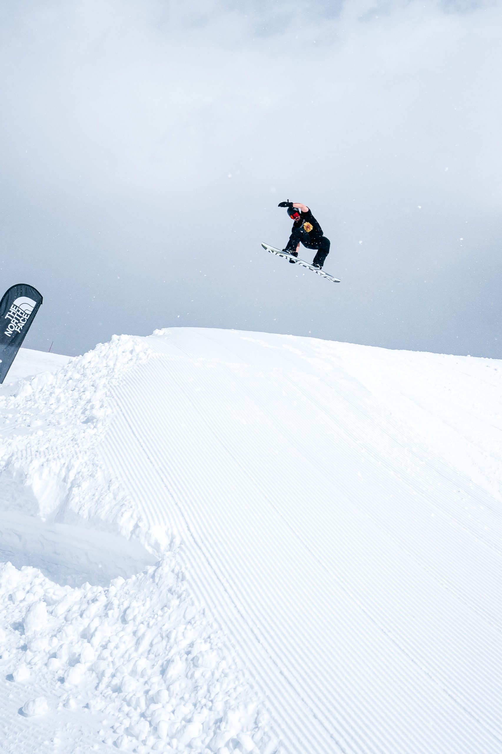 Snowboarder suspended mid-air above a groomed lip