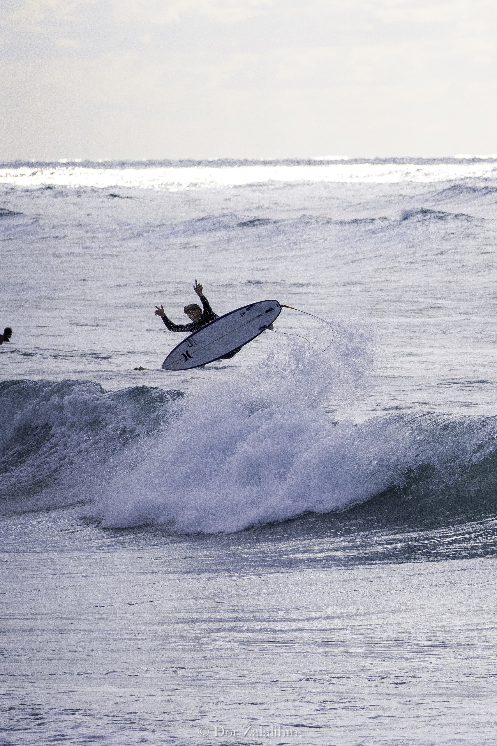 Surfer launching an air on a grey morning